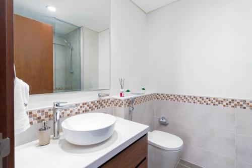 a white bathroom with a sink and a toilet at Delightful 2BR apartment at Reva Residences in Dubai