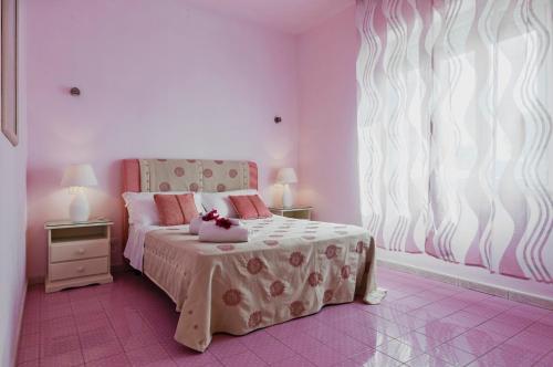 a pink bedroom with a bed and a window at Calliope's Apartments - Stella del Mare in Siracusa