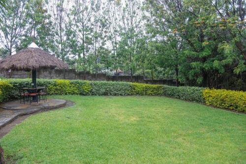 a lawn with a table and a straw umbrella at Dovenest Lodge in Naivasha