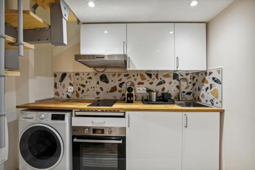 eine Küche mit weißen Schränken, einer Waschmaschine und einem Trockner in der Unterkunft Hyper centre Écusson - Magnifique T1 au calme in Montpellier