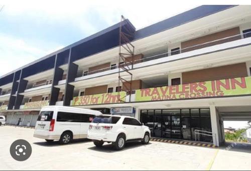 two white vehicles parked in front of a building at Travelers Inn Matina in Davao City