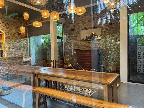 una sala da pranzo con tavolo in legno e panche di Đường Lâm Village a Sơn Tây