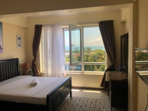 a bedroom with a bed and a large window at The Penthouse oysterbay in Dar es Salaam