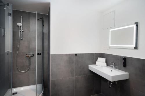 La salle de bains est pourvue d'un lavabo et d'une douche. dans l'établissement DIWOTEL l RÜSSELSHEIM, à Rüsselsheim