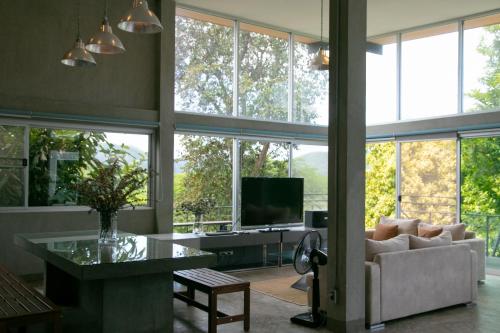 a living room with large windows and a couch at Mighty Mountain Thailand in Kaeng Krachan
