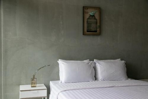 a bed with white pillows and a picture of a bird at Mighty Mountain Thailand in Kaeng Krachan