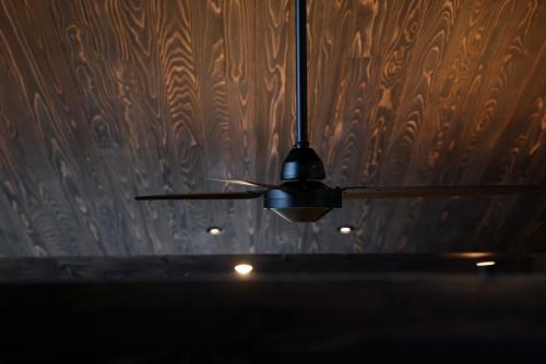 a ceiling fan in a room with a wooden wall at Hakuba Aurora Chalet by Jade Group in Hakuba
