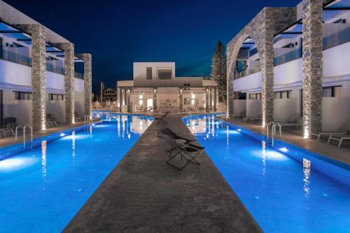 a pool at night with a chair in front of a building at Cavo di Suites in Kalamaki
