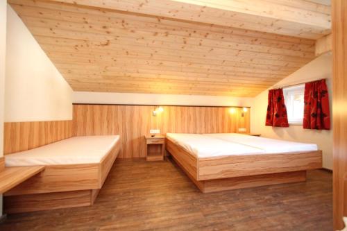 Habitación con 2 camas, paredes de madera y suelo de madera. en Ferienwohnung Königsleiten 2 - Top 1, en Wald im Pinzgau