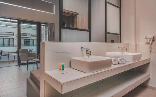 uma casa de banho com um lavatório e um espelho em Cavo di Suites em Kalamaki
