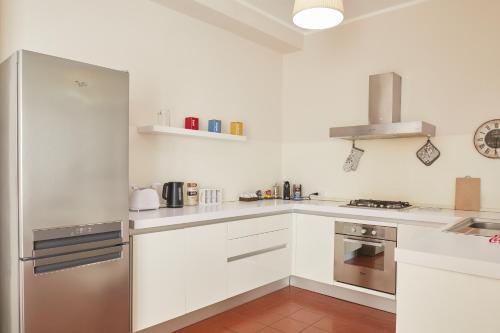 cocina con armarios blancos y nevera de acero inoxidable en Piazza Centrale - Spazio, Comfort e WiFi, en Civitanova Marche