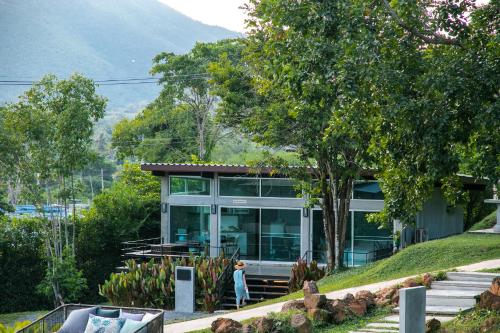 a woman walking in front of a house at Mighty Mountain Thailand in Kaeng Krachan