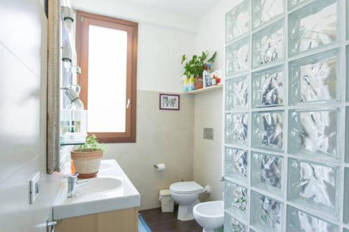 baño con lavabo y aseo y ventana en Mari & Popi’s House, en Mestre