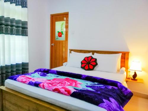 a bedroom with a bed with a colorful blanket at Heaven Hills Guest House in Maskeliya