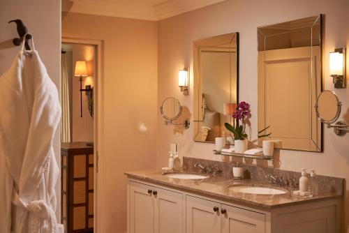 a bathroom with two sinks and a large mirror at Leeu House in Franschhoek