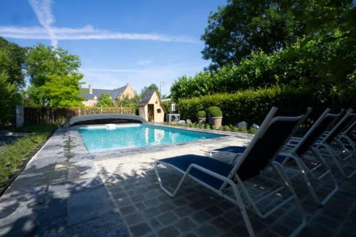 a swimming pool with two chairs and a house at Au Chantecler in Malzy