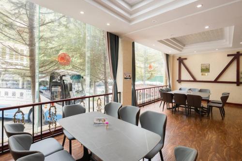 a restaurant with tables and chairs and a large window at Jiuzhai Journey Hotel in Jiuzhaigou
