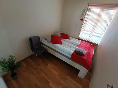 a bedroom with a bed with red pillows and a window at Apartment right in the city centre in Stavanger