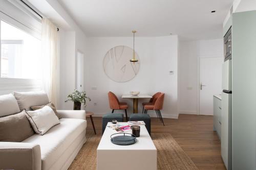 een woonkamer met een witte bank en een tafel bij Tetuán 15 Boutique Apartments by Hommyhome in Sevilla
