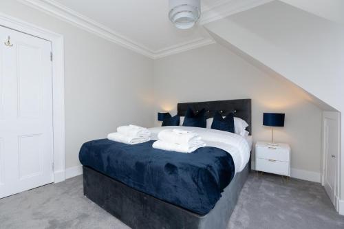 Luxury 3 Bed Apartment in Aberdeen City Centre. في أبردين: غرفة نوم بيضاء مع سرير كبير مع شراشف زرقاء