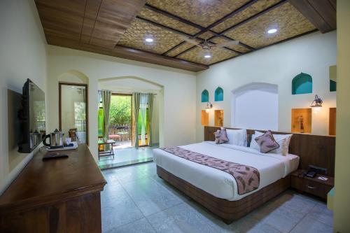 a bedroom with a large bed and a desk at Sterling Padam Pench in Khawāsa