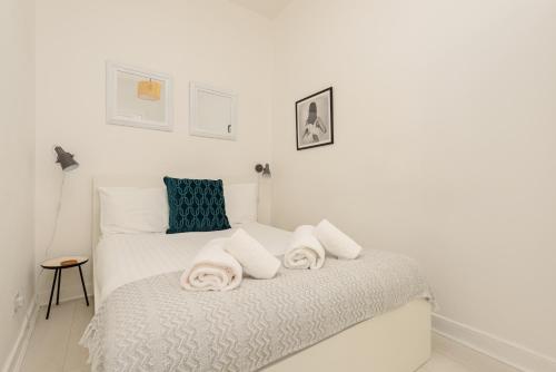 een witte slaapkamer met een bed met handdoeken erop bij The Tollcross Apartment - Modern & Bright 1BR in Edinburgh