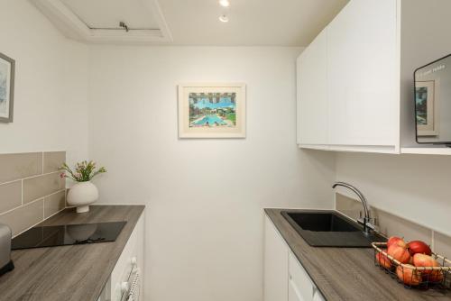 een witte keuken met een wastafel en een fruitschaal bij The Tollcross Apartment - Modern & Bright 1BR in Edinburgh