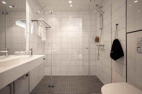 a bathroom with a shower and a toilet and a sink at Home Hotel Arcticus in Harstad
