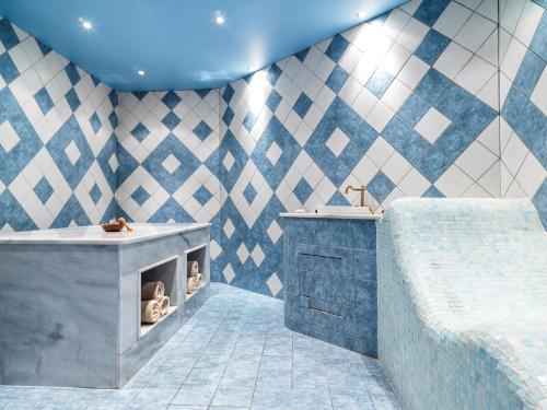 baño azul y blanco con bañera y lavamanos en Leonardo Plaza Cypria Maris Beach Hotel & Spa, en Pafos