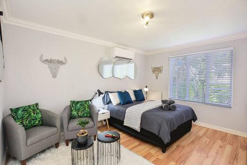 a bedroom with a bed and a couch and a chair at Flatlet 2.1km from Iconic Blaauwberg Beach in Cape Town