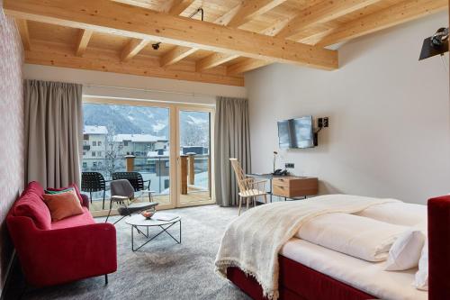 a bedroom with a large bed and a red chair at Huber's Boutique Hotel in Mayrhofen