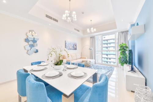 a dining room with a white table and blue chairs at Dunya Tower · Downtown Luxury · 5 Min Walk To Dubai Mall! in Dubai