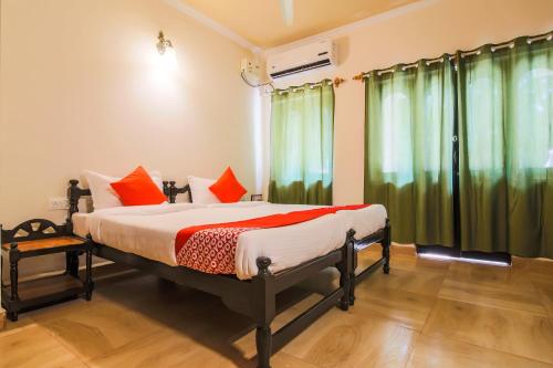 um quarto com uma cama com cortinas verdes em OYO La Petite Near Dabolim Airport em Chicolna