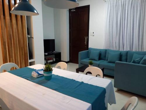 uma sala de estar com uma mesa e um sofá azul em GLC SUITES em Bislig