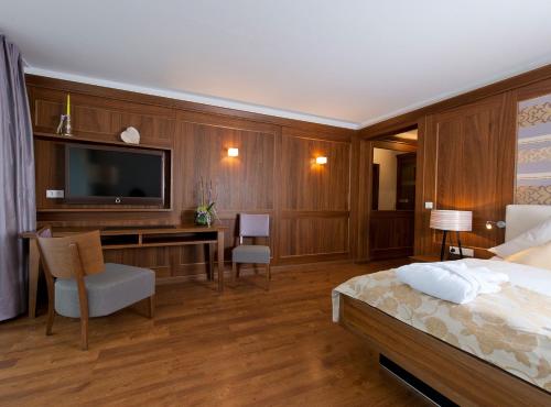 a bedroom with a bed and a desk with a television at Hotel Heinzler am See in Immenstaad am Bodensee