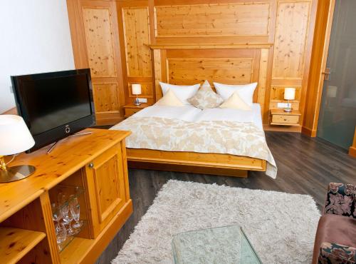 a bedroom with a bed and a desk with a television at Hotel Heinzler am See in Immenstaad am Bodensee
