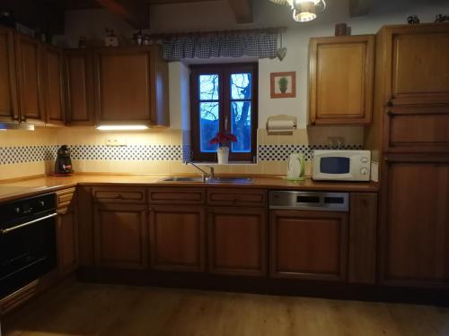 a kitchen with wooden cabinets and a microwave and a window at Chalupa Rejvíz in Rejvíz