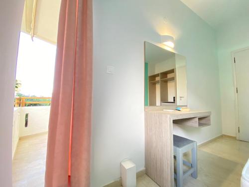 Habitación con espejo, escritorio y ventana. en Domenica Apartments, en Rethymno