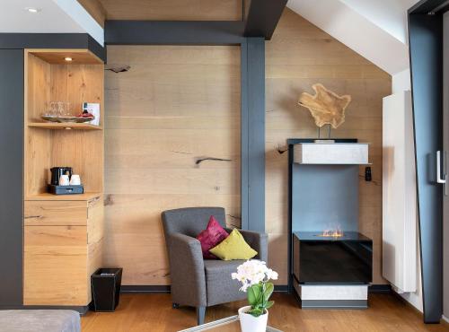 a living room with a chair and a fireplace at Hotel Heinzler am See in Immenstaad am Bodensee