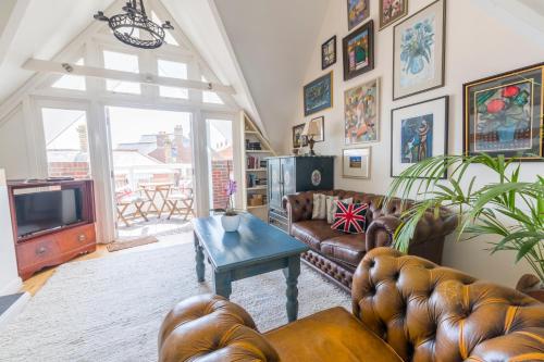 uma sala de estar com sofás de couro e uma televisão em Britannia House em Lymington