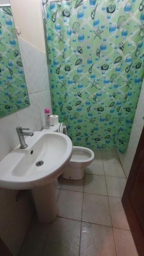 a bathroom with a sink and a toilet with a shower curtain at Spacious 2bedroom condo w free parking on premises in Nairobi