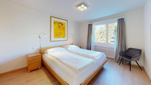 a bedroom with a bed and a chair and a window at Alpensonne in St. Moritz