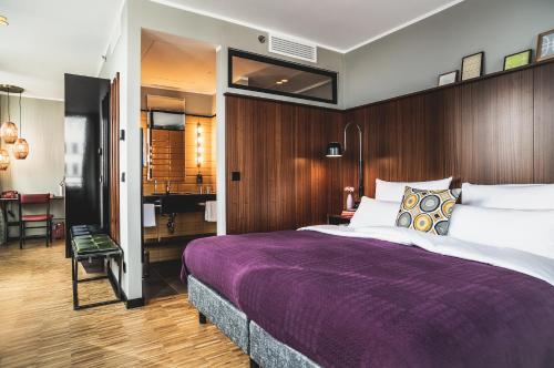 a bedroom with a large bed with a purple blanket at Henri Hotel Düsseldorf Downtown in Düsseldorf