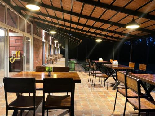 a restaurant with wooden tables and chairs and a patio at Coffeeberry Hills Chikamagalur in Chikmagalūr