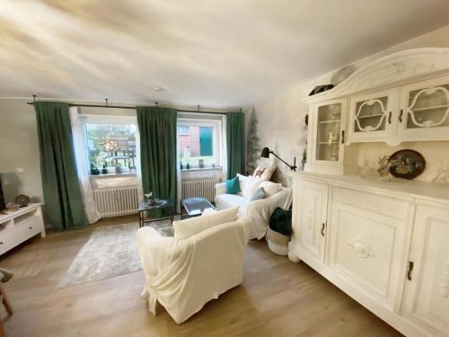 a living room with white furniture and green curtains at Christianes Apartment - Ebstorf in Ebstorf