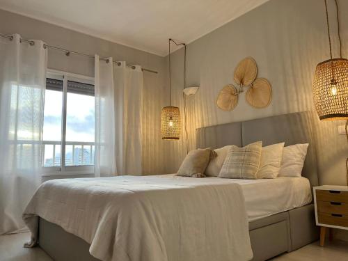 a bedroom with a bed with white sheets and a window at Saltwater Apartment in Portimão
