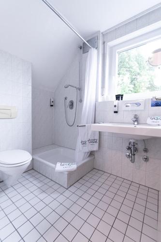 a white bathroom with a tub and a toilet at Taste Smart Hotel Backnang in Backnang