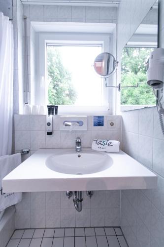 a white bathroom with a sink and a window at Taste Smart Hotel Backnang in Backnang