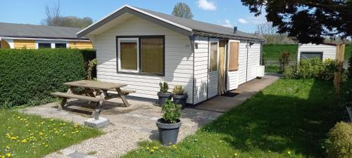 a white shed with a picnic table and a bench at Rekerlanden 241 in Schoorldam