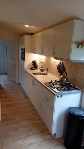 a white kitchen with a sink and a stove at Rekerlanden 241 in Schoorldam